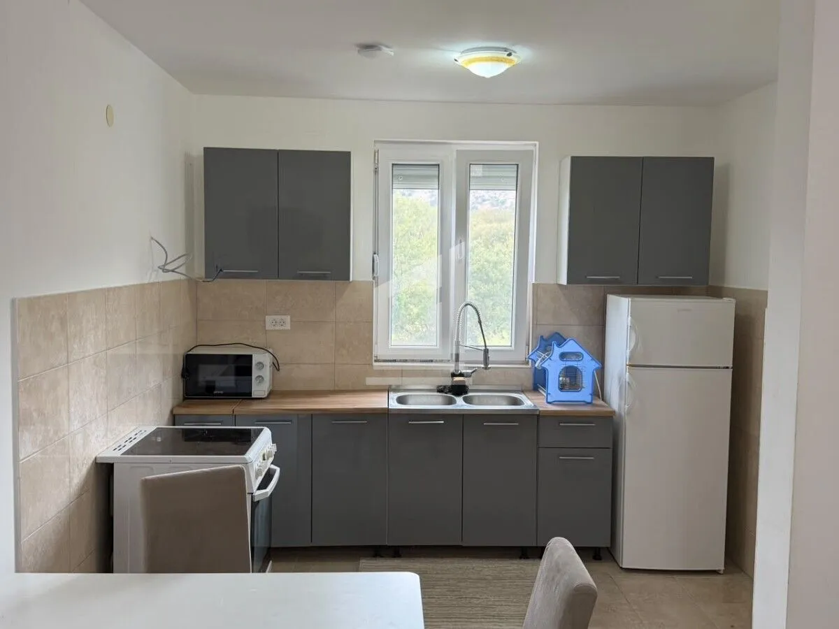 Small kitchen with grey cabinets, white appliances and a window.