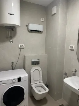 Moderne kupatilo sa veš mašinom, wc šoljom i umivaonikom obloženo sivim pločicama. - image 10