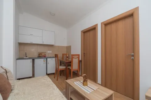 Manja kuhinja sa trpezarijskim stolom i drvenim elementima u stanu. - image 2