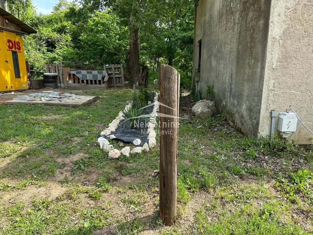Dvorište kuće sa zelenilom i pomoćnim objektom.