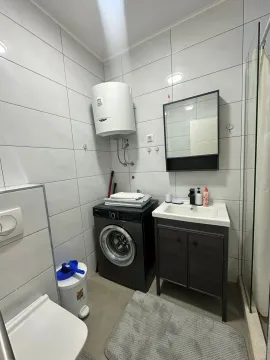 Manje kupatilo sa bijelim pločicama, umivaonikom i veš mašinom. - image 5