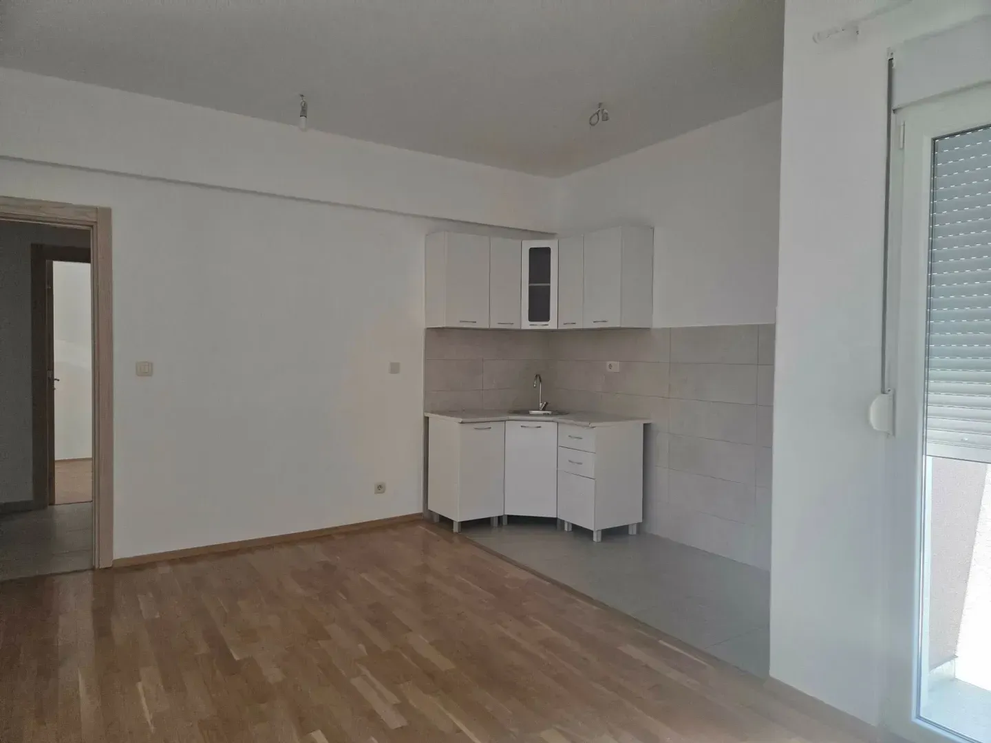 Living room with a small kitchen and parquet flooring.