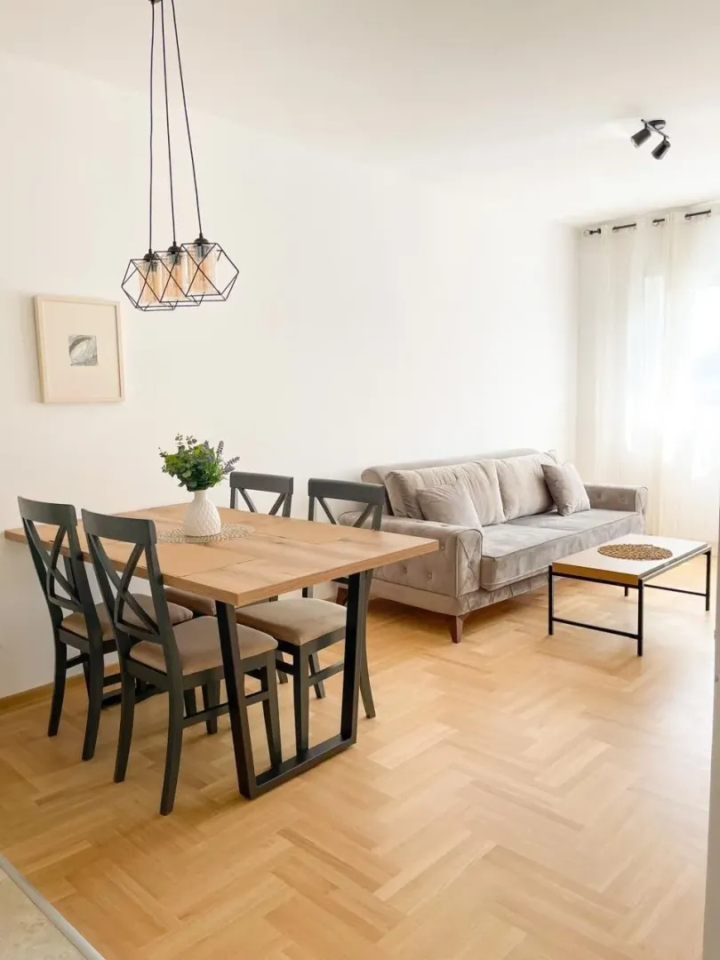 Living room with dining area, sofa and wooden flooring.