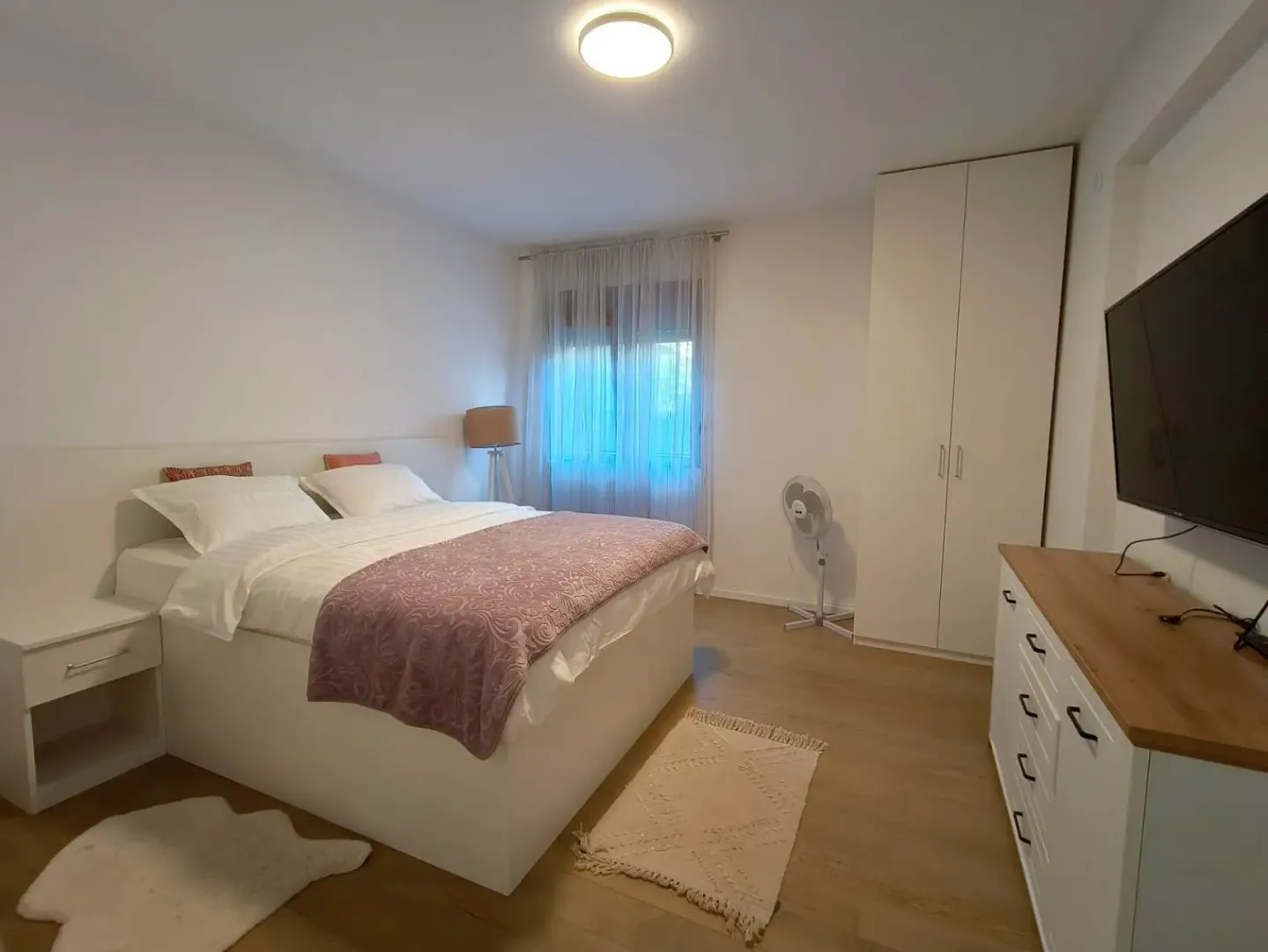 Furnished bedroom with a double bed, wardrobe, and TV.