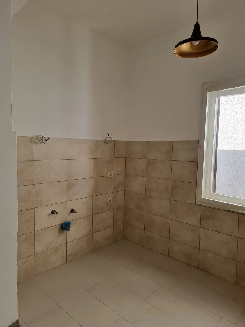 Empty kitchen space with tiling and installed lighting fixture.