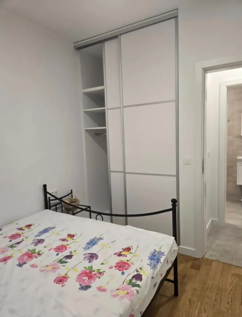 Manja spavaća soba sa krevetom i ugradnim plakarom.