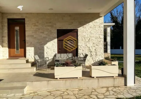 Covered terrace in front of the house entrance with seating furniture and stone facade. - image 8