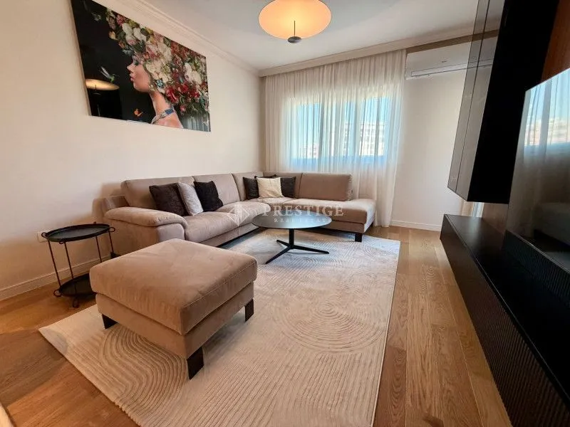 Comfortable living room with a sectional sofa, rug, and a large art piece on the wall.