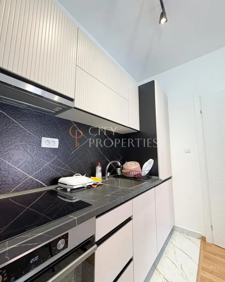 View of a modernly equipped kitchen with a built-in oven, cooktop, and sink.