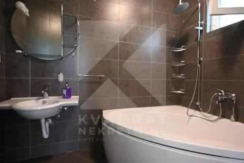 Bathroom equipped with a bathtub, washbasin, and a mirror with shelves. - image 26
