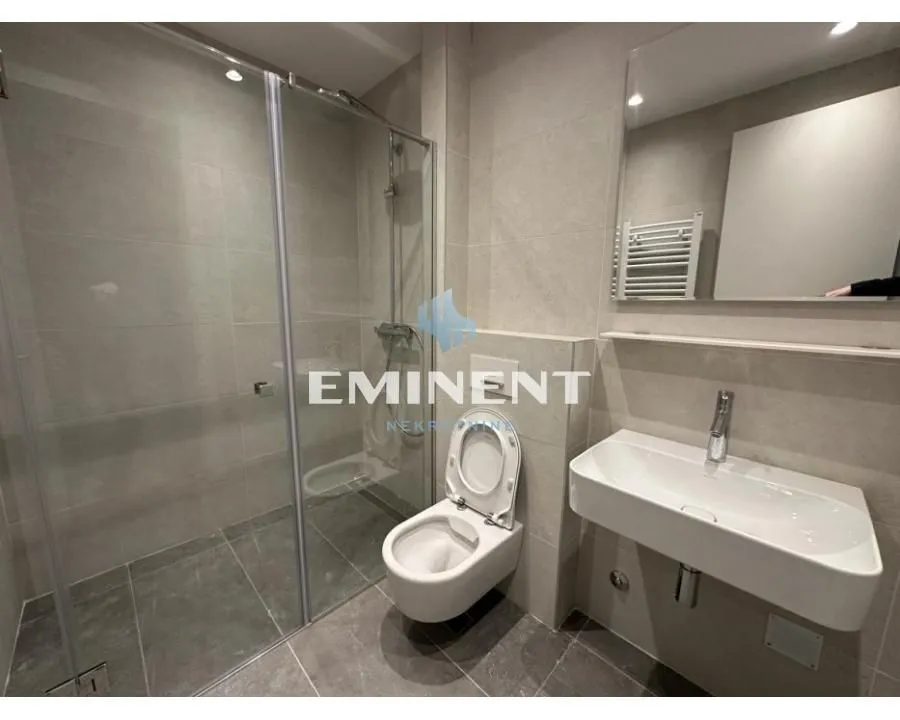 Modern bathroom with a walk-in shower, washbasin, and toilet.
