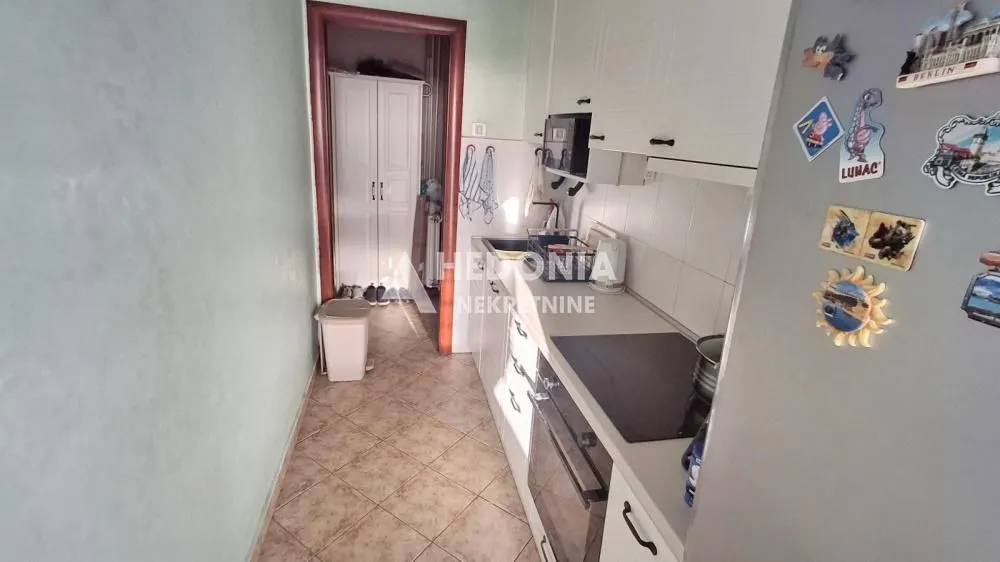 Manja kuhinja sa belim elementima i ugradnom pločom.