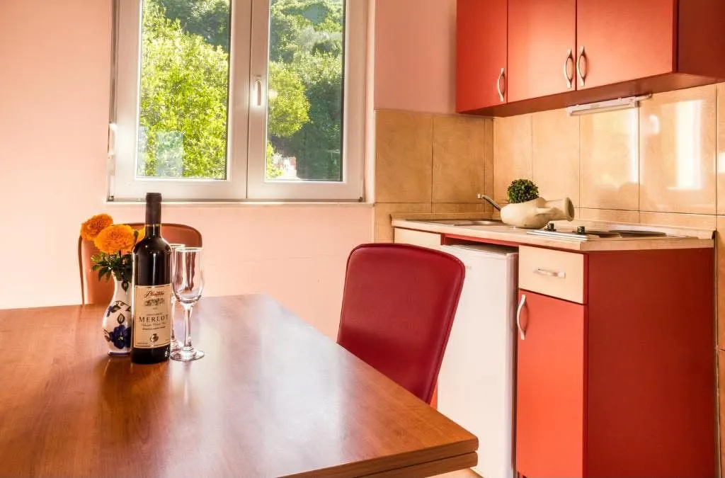 Small kitchen with red cabinets and a dining table by the window.