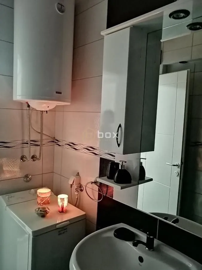 View of the bathroom with a sink, mirrored cabinet, and water heater.