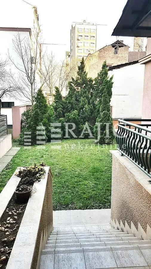 Pogled sa stepeništa na uređeno dvorište i zelene površine.