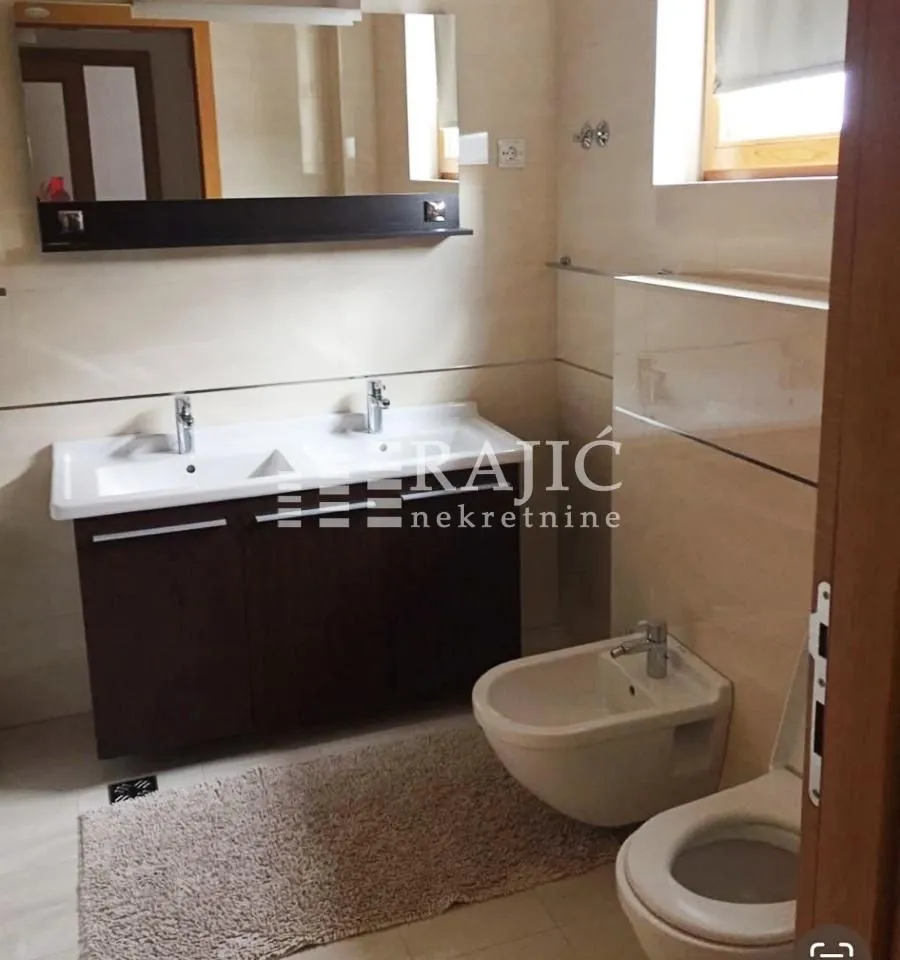 Furnished bathroom with two sinks, a mirror, and sanitary fixtures.