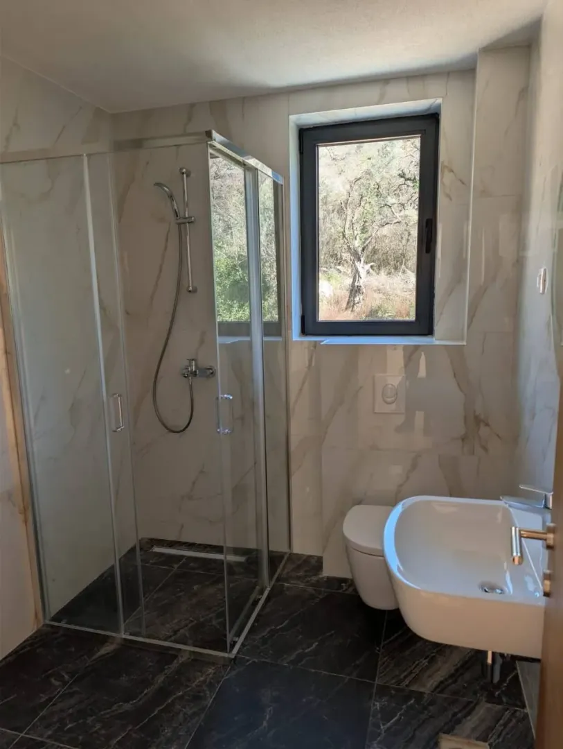 Moderne kupatilo sa tuš kabinom, umivaonikom i wc šoljom.
