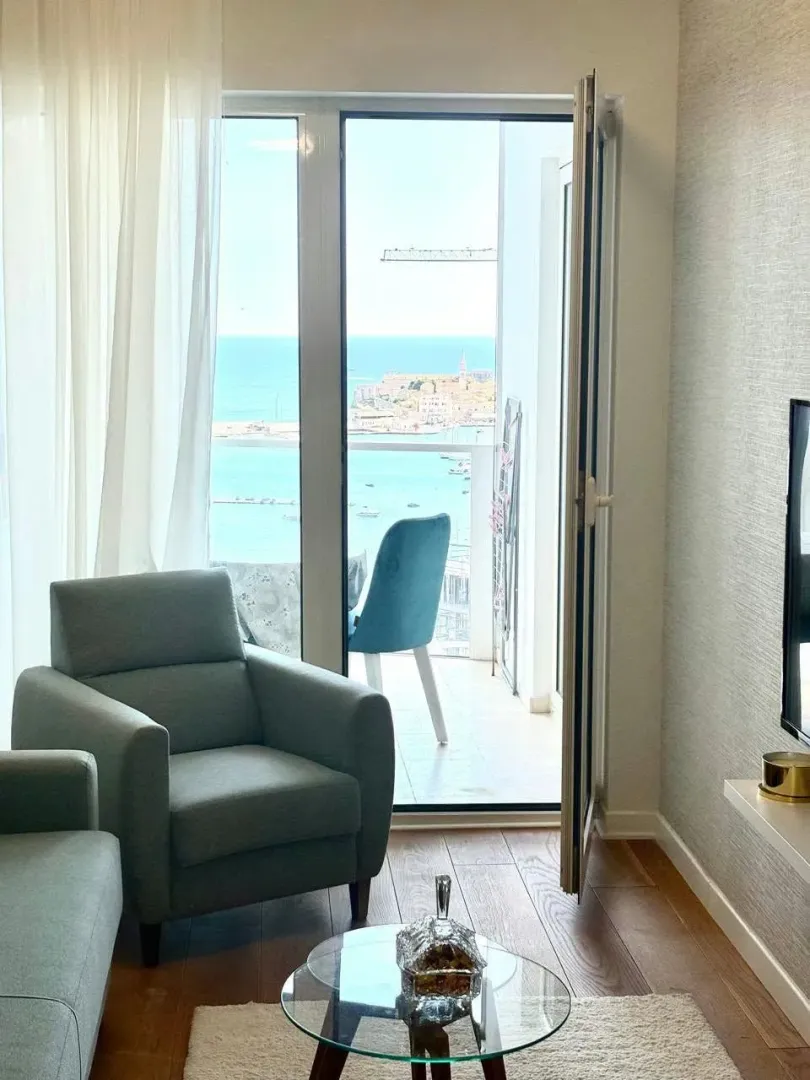 Living room with furniture and a sea view through the balcony door.