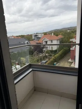Manji balkon sa staklenom ogradom i pogledom na okolno naselje. - image 17