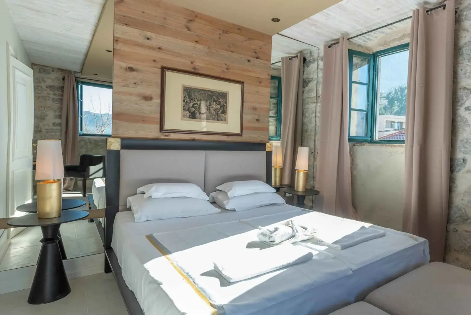 Furnished bedroom with a double bed, wooden wall panels, and exposed stone walls.