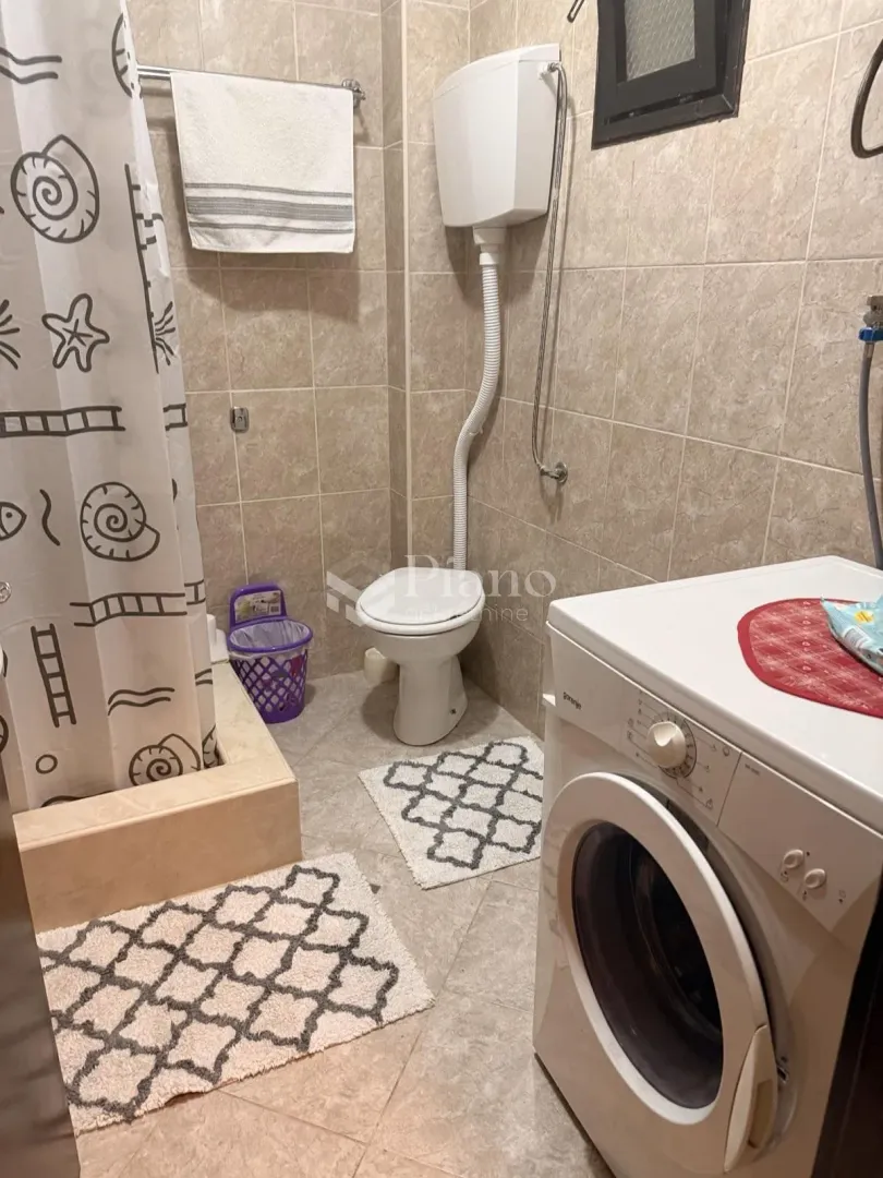 Compactly equipped bathroom with a shower enclosure, toilet, and washing machine.