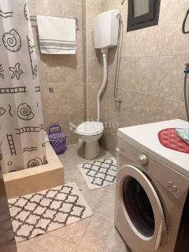Compactly equipped bathroom with a shower enclosure, toilet, and washing machine. - image 5