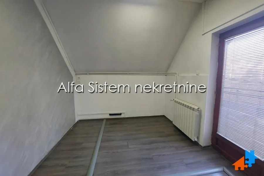 Empty attic room with laminate flooring, sloped ceiling and a door leading to the terrace.