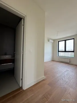 Prazna soba sa parketom i otvorenim vratima kupatila. - image 6