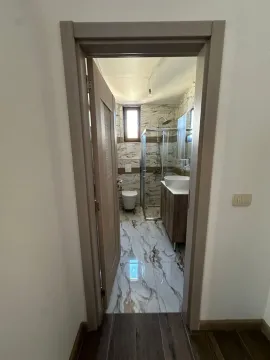 Pogled kroz otvorena vrata na moderno kupatilo sa tuš kabinom. - image 6