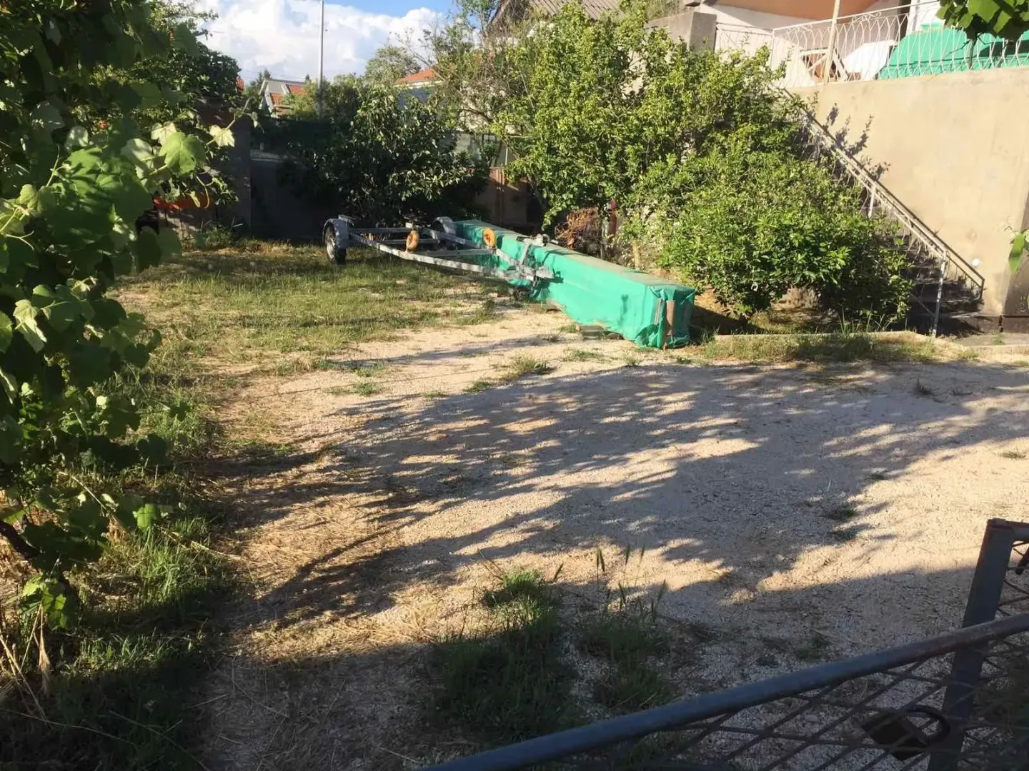 Spacious house yard with greenery and a gravel driveway.