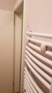 Beli radijator za peškire montiran na zid u kupatilu. - image 21