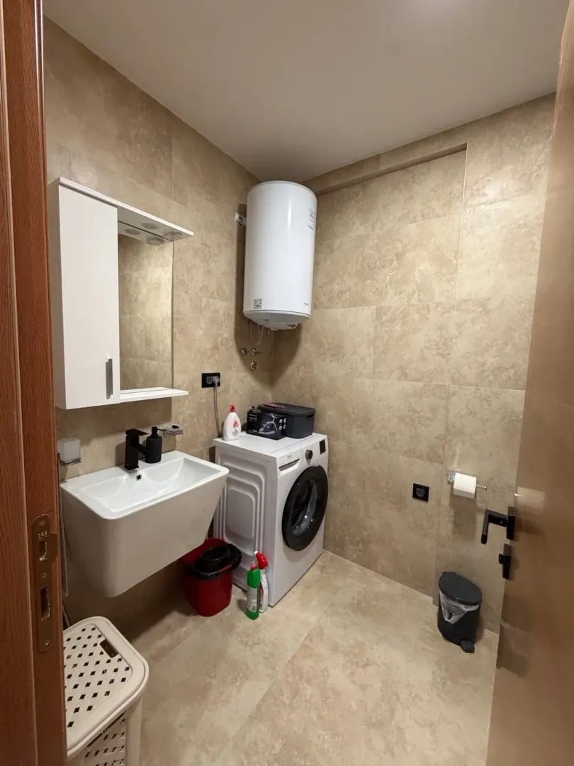Small bathroom with a sink, washing machine, and water heater.