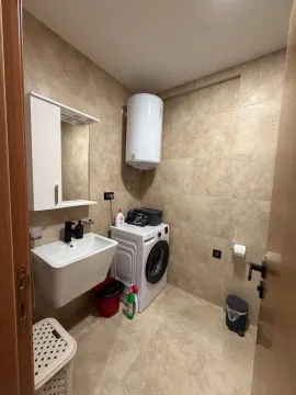 Small bathroom with a sink, washing machine, and water heater. - image 9