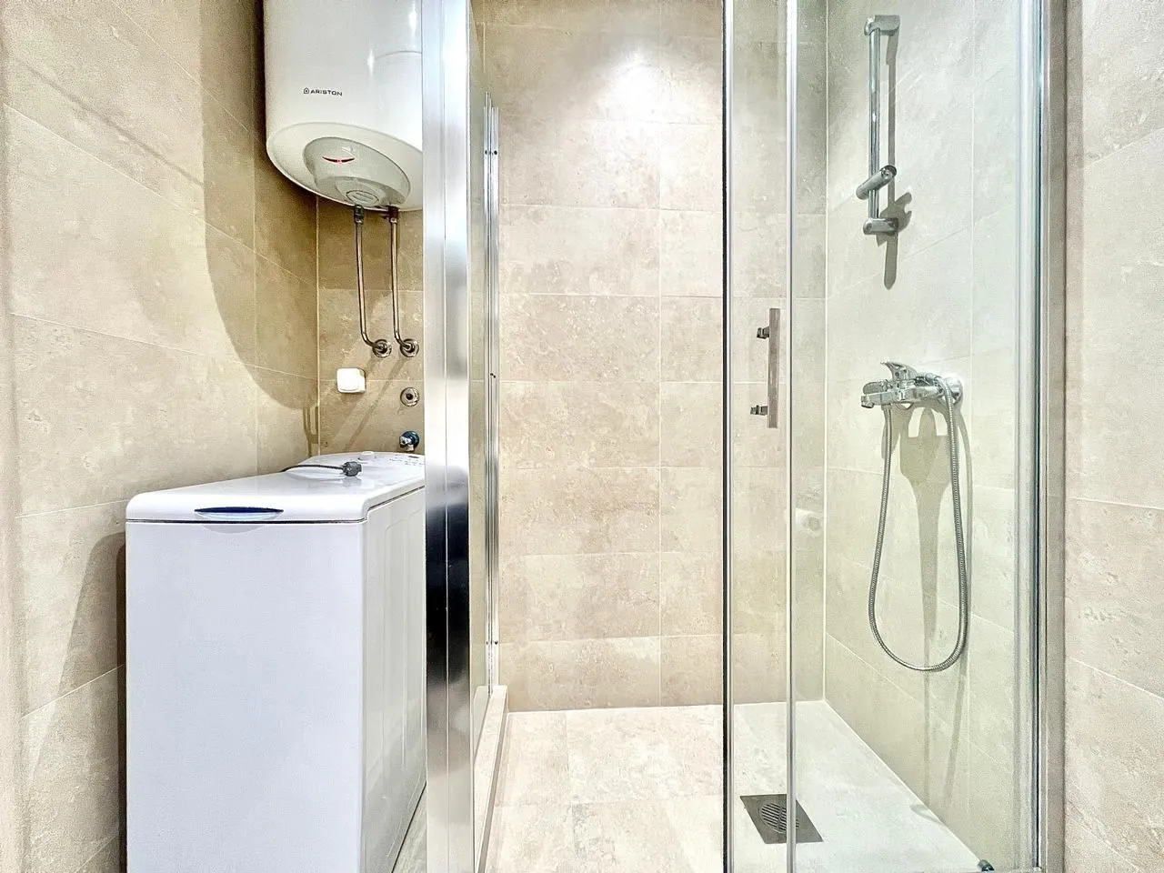 Bright bathroom with a shower cabin and washing machine.