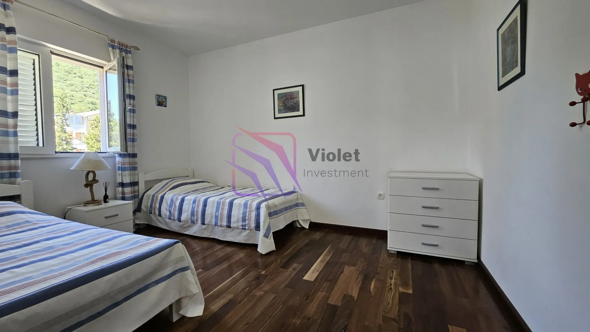 Spavaća soba sa dva kreveta, komodom i prozorom.