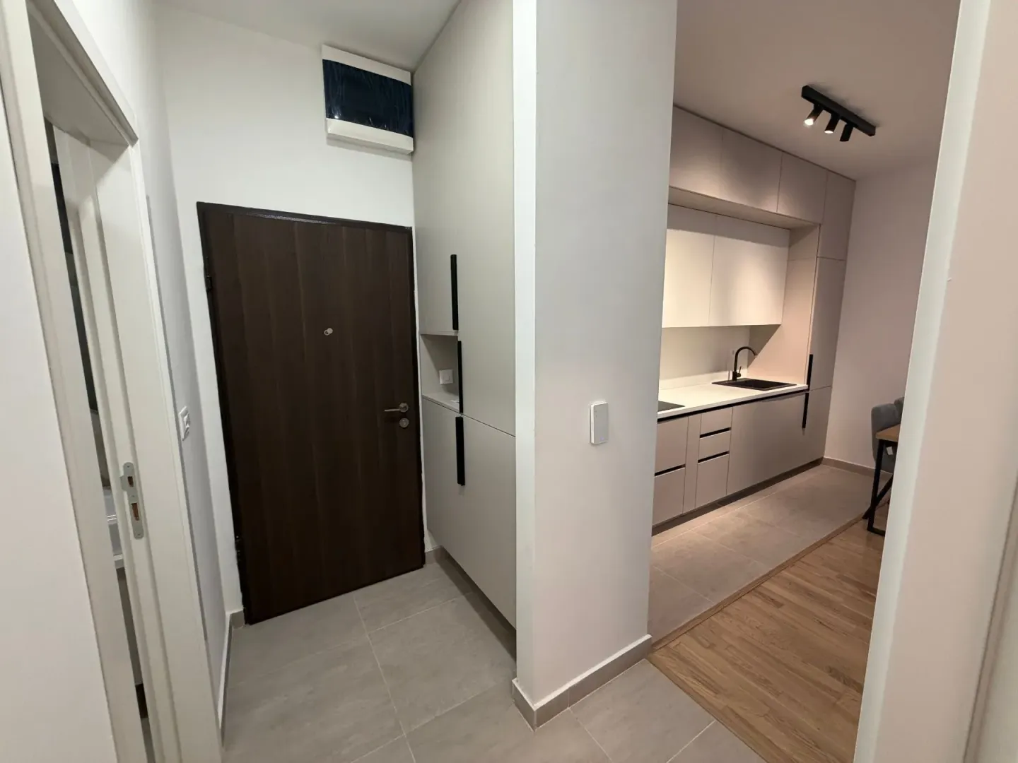Hodnik sa ulaznim vratima i pogledom na moderno opremljenu kuhinju.