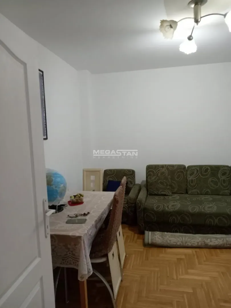 Dnevna soba sa garniturom za sedenje i trpezarijskim stolom.