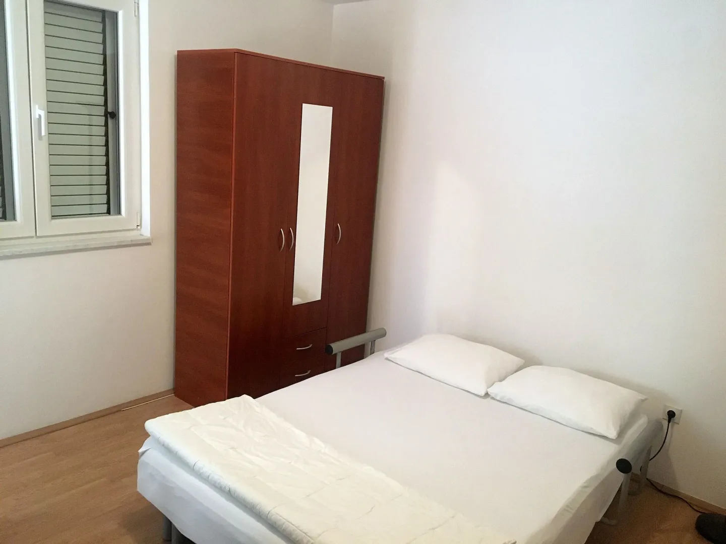 Spavaća soba sa krevetom i drvenim ormarom.