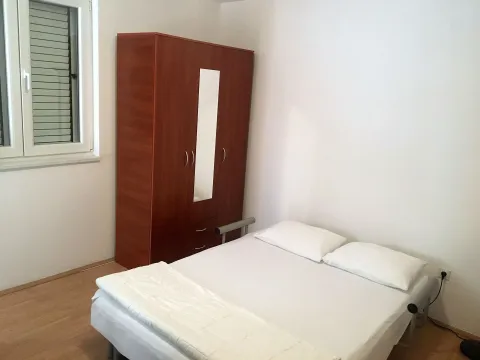 Spavaća soba sa krevetom i drvenim ormarom. - image 4