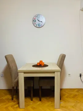 Manji trpezarijski sto sa dvije stolice i ukrasnim satom na zidu. - image 2