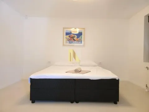 Uređena spavaća soba sa bračnim krevetom i umetničkom slikom na zidu. - image 10