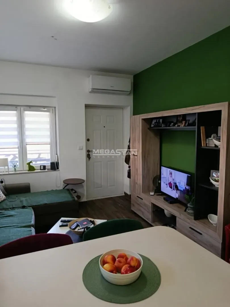 Living room with sofa, TV, and dining table.