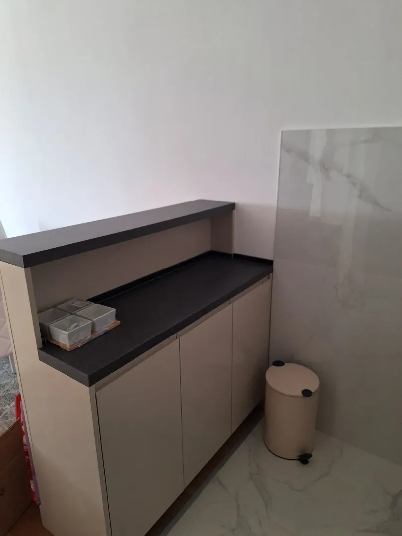 Moderni kuhinjski element sa tamnom radnom pločom i keramičkim podom.
