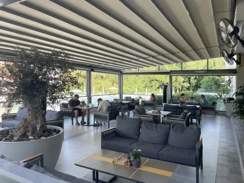 Covered terrace with seating furniture and a view of the pool. - image 20