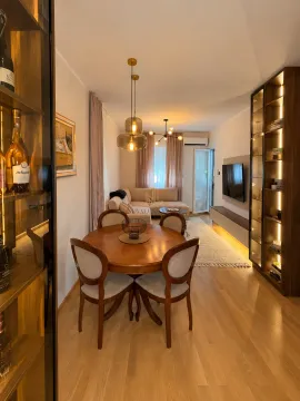 Living room with a dining area, a wooden table and built-in illuminated shelves. - image 3
