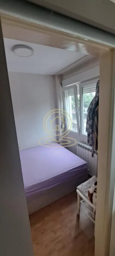 Manja spavaća soba sa bračnim krevetom i prozorom.