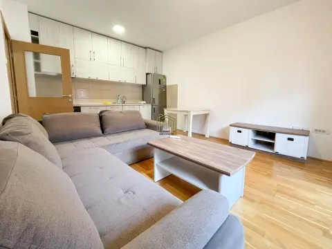 Dnevna soba sa ugaonom garniturom i kuhinjom u pozadini. - image 3