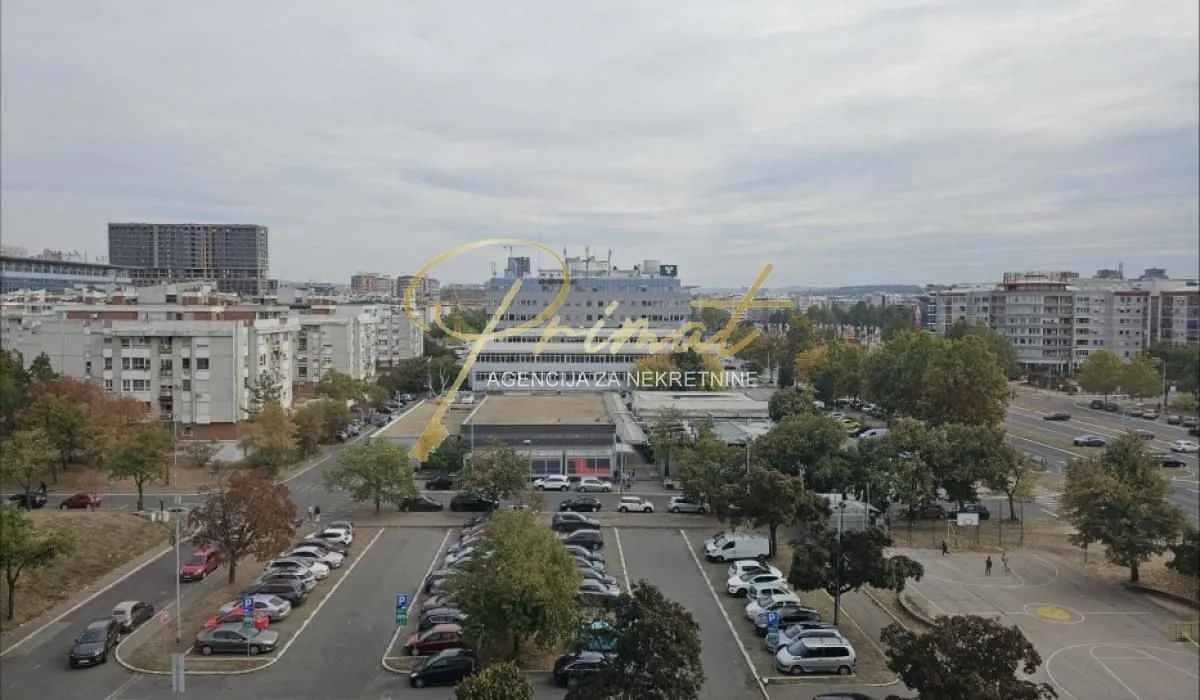 Pogled sa prozora na okolne zgrade, parking i gradsku zonu.