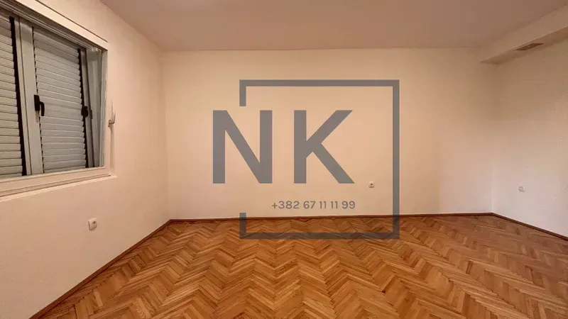 Empty room with parquet flooring and a single window.