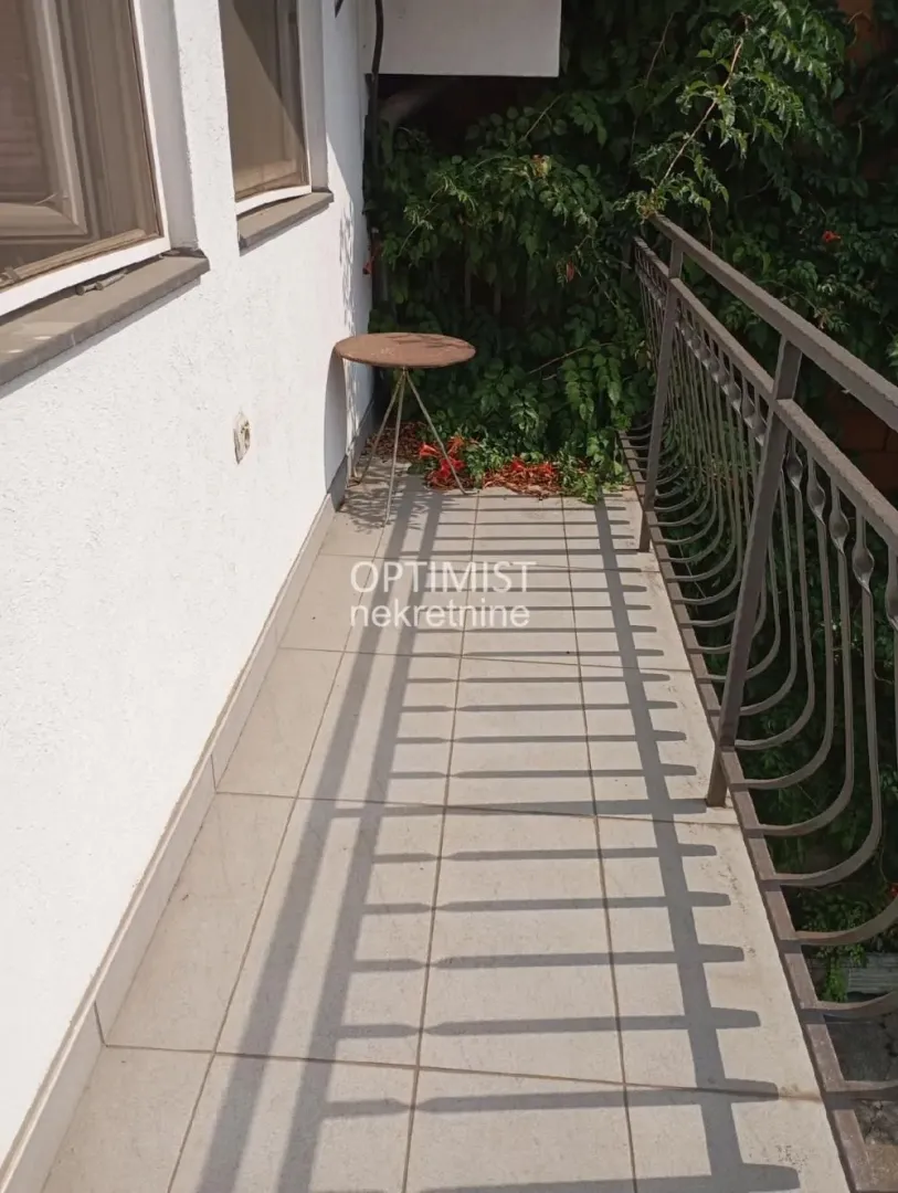 Small tiled balcony with a metal railing and a small table.